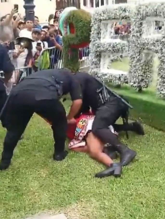 Picture of Gahela Cari being arrested by 2 police officers.