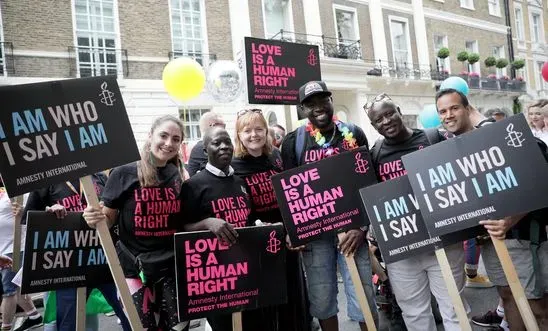 Image of people holding signs that say "I am who I say I am, and "love is a human right."
